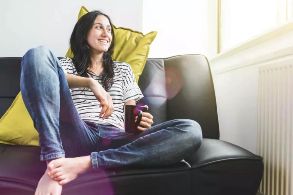 Günstige Gaspreise für ein warmes Zuhause Frau sitz mit Kaffeetasse auf der Couch und freut sich über die günstigen Gaspreise bei lekker Energie